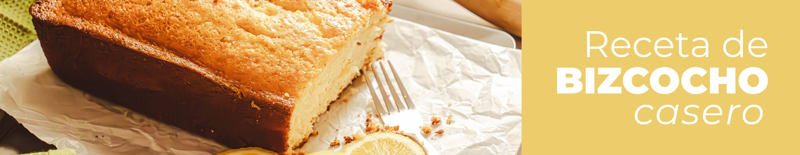 Bizcocho esponjoso y casero junto con unos limones sobre una encimera de madera.